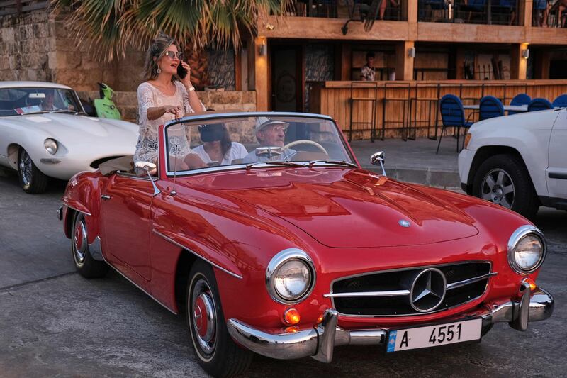 A woman sits in a two-door 1961 Mercedes Benz 190 SL during a parade at the port.