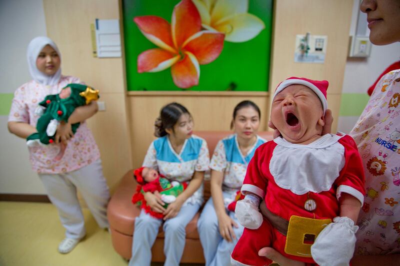 Nurses at a Bangkok hospital hold up newborns dressed in Santa and Christmas tree outfits. Gemunu Amarasinghe / AP Photo