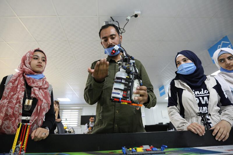 Syrian refugee students and instructor, Yasine Hariri, use his invention that is a robot prototype that automatically dispenses sanitiser to avoid contact and combat the spread of the coronavirus disease (COVID-19) as a part of the camp's UNHCR-led Innovation Lab program, at the Zaatari refugee camp in the Jordanian city of Mafraq, near the border with Syria. REUTERS