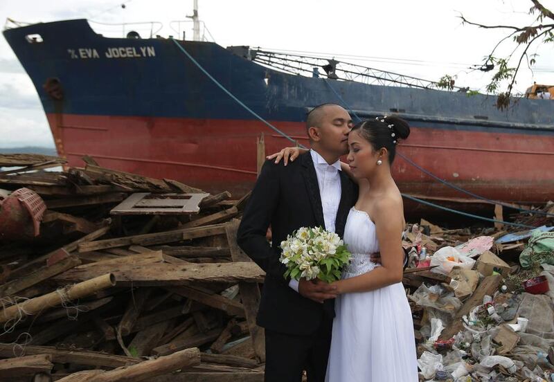 Filipino groom Earvin Nierva, left, and his wife, Rise, pose for their wedding pictures beside damaged homes and a ship that was washed ashore to symbolise they can overcome tragedy.  Aaron Favila / AP