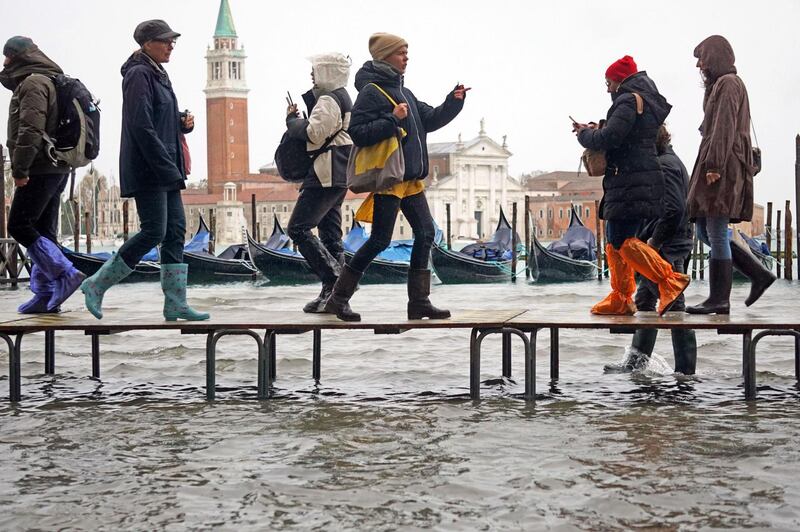 People walk on benches through floodwaters. EPA