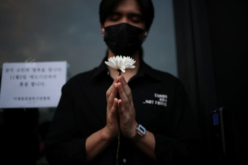 A man holds a floral tribute near the scene of a deadly crowd surge that killed more than 154 people and injured 149 during Halloween festivities in Itaewon district in South Korea's capital Seoul. Reuters