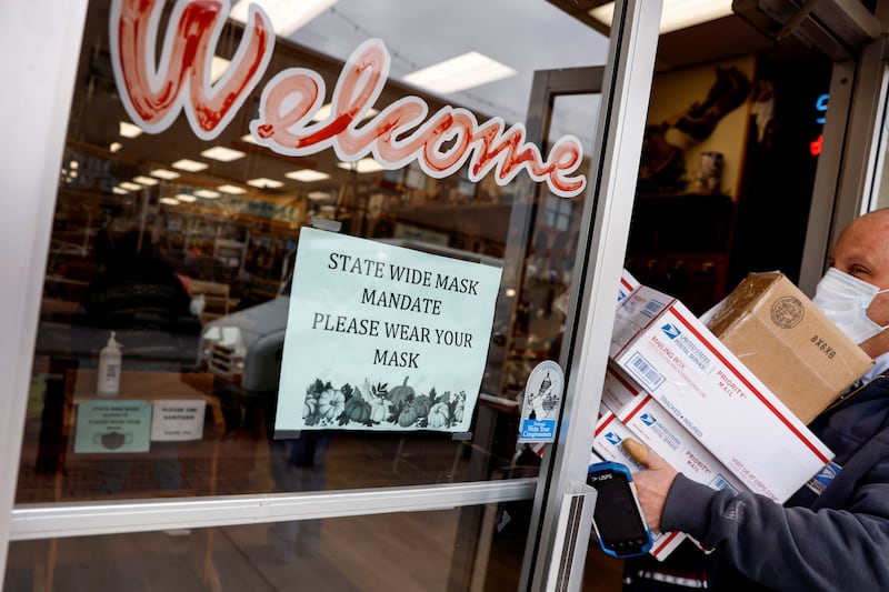 A US postal worker makes a delivery while wearing a face mask, at a store in Gallup, New Mexico, US , December 7. Reuters
