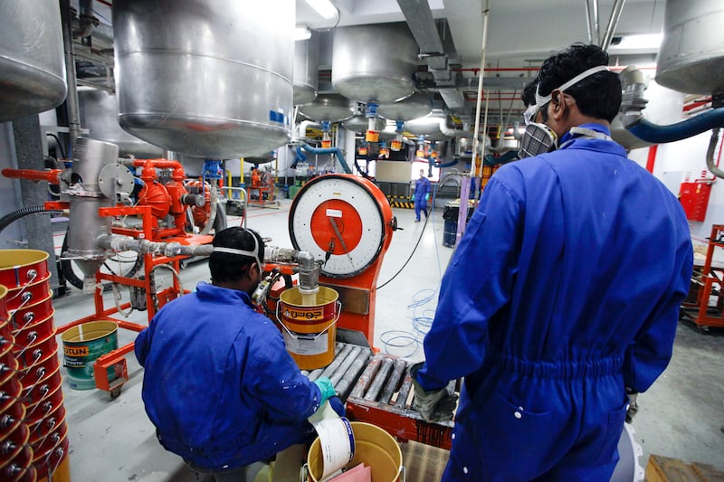 Abu Dhabi, February 27, 2013 - Jotun workers continue their tasks while inspectors from the Abu Dhabi Environment Agency carry out a routine environmental check at a Jotun paint manufacturing factory in Abu Dhabi, February 27, 2013. (Photo by: Sarah Dea/The National)