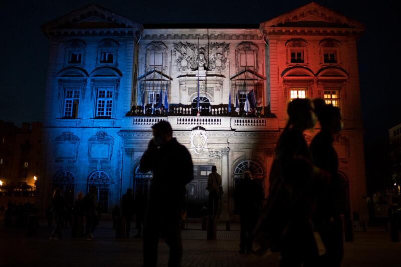 Pedestrians walk past Marseille's town hall lit up in the French Tricolor to honor slain teacher Samuel Paty, Wednesday, October 21, 2020. AP Photo