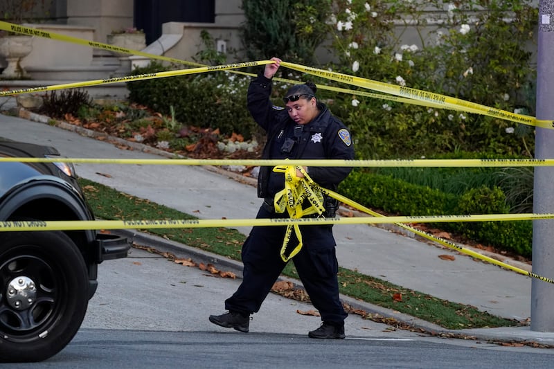 A police officer rolls out yellow tape near the Pelosi residence. The attack on Mr Pelosi comes before the US midterms and is the latest violence against a political figure. AP