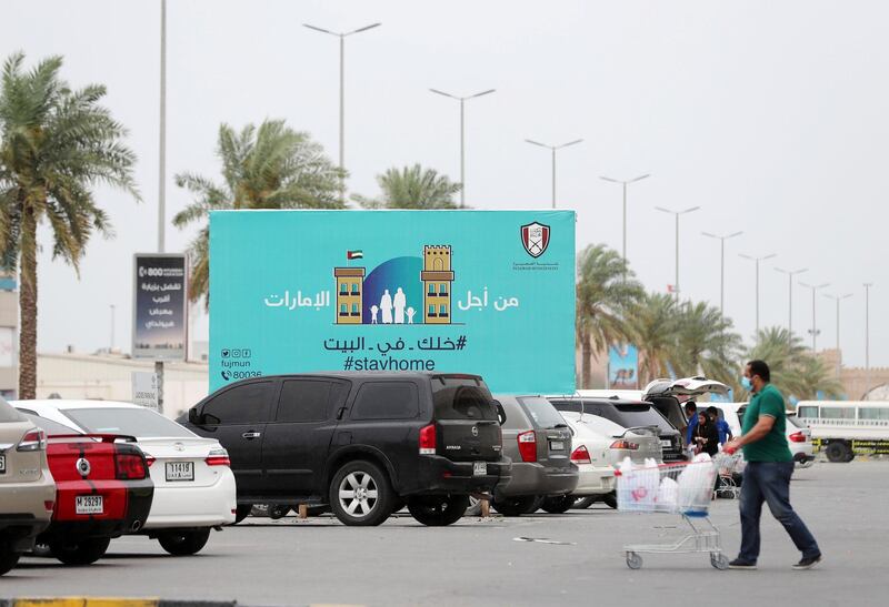 Fujairah, United Arab Emirates - Reporter: N/A: Corona. A sign in Fujairah urges people to 'Stay Home' as people do their shopping. Wednesday, April 15th, 2020. Fujairah. Chris Whiteoak / The National