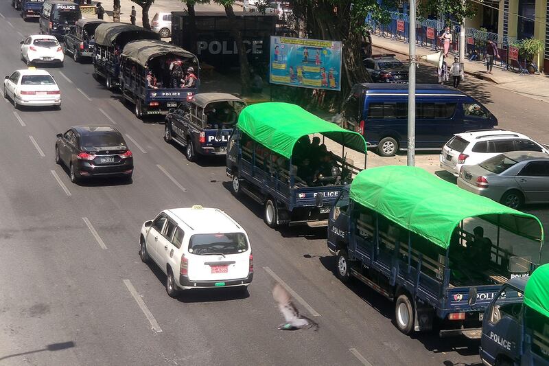 Cars pass police sitting in trucks along a road in Yangon, as Myanmar's military detained the country's de facto leader Aung San Suu Kyi and the country's president in a coup. AFP