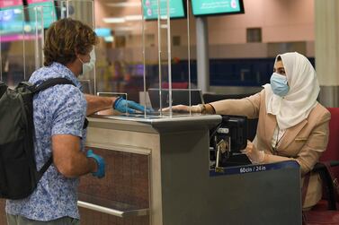 A passenger of an Emirates airlines flight departing to the Australian city of Sydney, checks in at Dubai International Airport on May 22, 2020, after the resumption of scheduled operations by the Emirati carrier, amid the ongoing novel coronavirus pandemic crisis. / AFP / Karim SAHIB