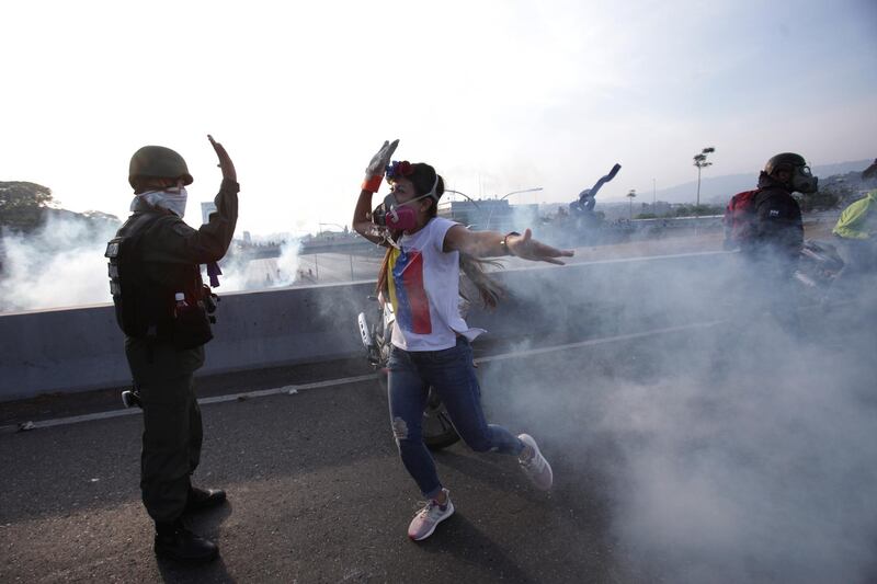 An opponent to Venezuela's President Nicolas Maduro high fives a rebel soldier on a highway overpass outside La Carlota air bas. AP Photo