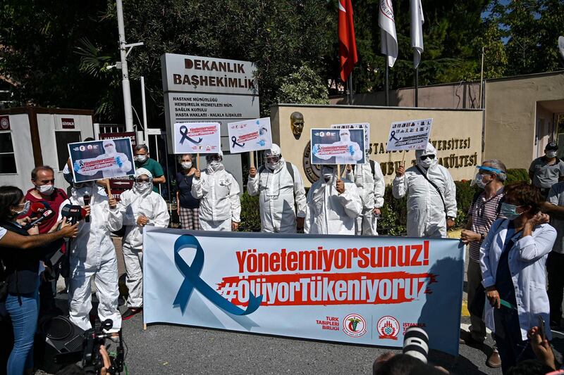 Turkey's health workers and doctors wearing personal protective equipment protest against government's policy in front of Istanbul University medical faculty.   AFP