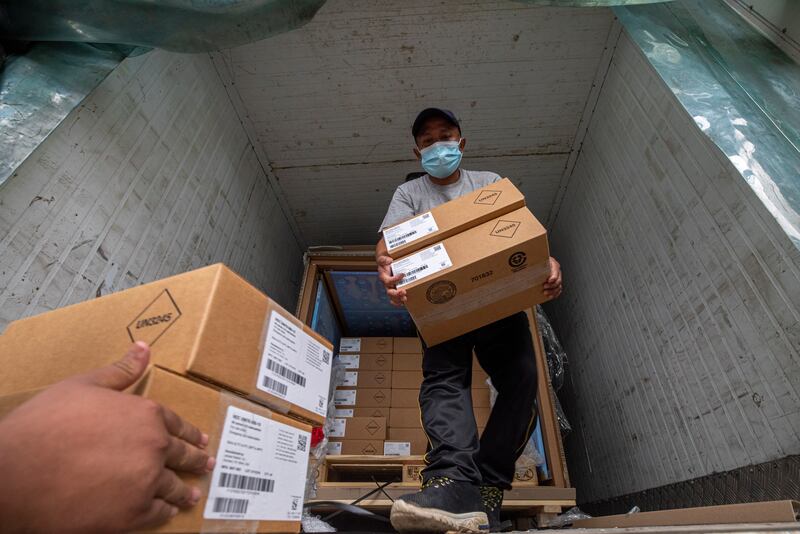 Nepalese workers unload boxes containing doses of the Johnson & Johnson vaccine in Kathmandu, Nepal.