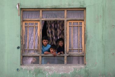 Afghan children look out from a broken window at the site of a blast in Kabul, Afghanistan, as the US and the Taliban near a peace deal. Reuters