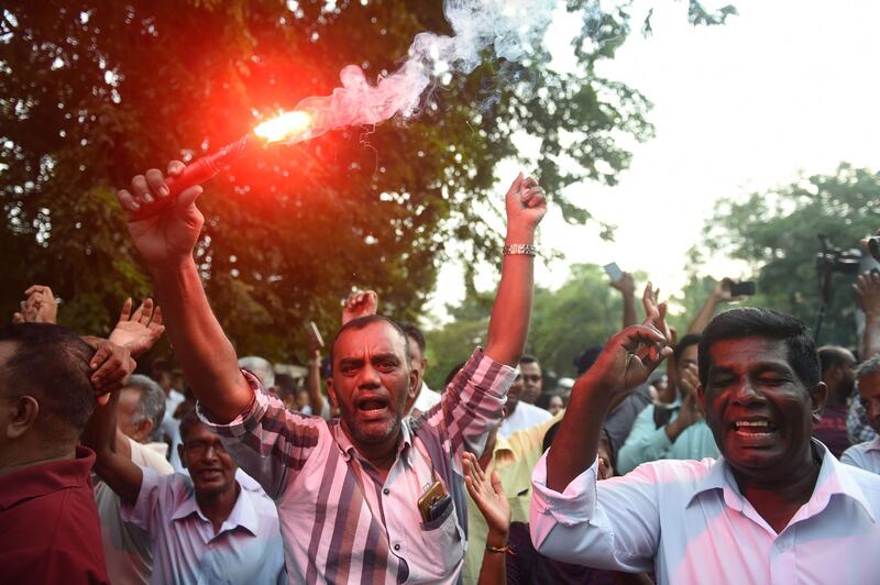 A supporter of ousted Sri Lanka's prime minister Ranil Wickremesinghe holds a flare and shout slogans with other supporters as they celebrate Sri Lanka's Supreme Court ruling outside the Sri Lankan Supreme Court in Colombo on December 13, 2018.  Sri Lanka's Supreme Court on December 13 ruled that President Maithripala Sirisena's sacking of parliament last month was illegal, clearing the way for potential impeachment proceedings against him.
 / AFP / ISHARA S. KODIKARA
