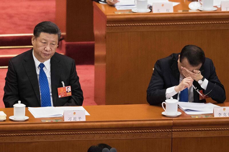 Premier Li Keqiang, right, covers his face in his hand as he and China's President Xi Jinping, left, attend the fourth plenary session of the National People's Congress at the Great Hall of the People in Beijing. China's rubber-stamp parliament on March 11 endorsed Xi's move to abolish rules limiting heads of state to 10 years in power. Nicolas Asfouri / AFP