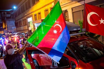 Members of Turkey's Humanitarian Relief Foundation (IHH) display Turkish and Azerbaijan flags on their vehicle before taking a tour in the city in solidarity with Azerbaijan, in Istanbul on October 5, 2020. Turkey on October 4, 2020 condemned what it said were attacks on civilians by Armenian forces on the Azerbaijani city of Ganja in the conflict over disputed breakaway region Nagorno-Karabakh. The fighting over Karabakh, which broke out into renewed fighting seven days ago, intensified as Armenian and Azerbaijani forces exchanged rocket fire.  / AFP / Yasin AKGUL
