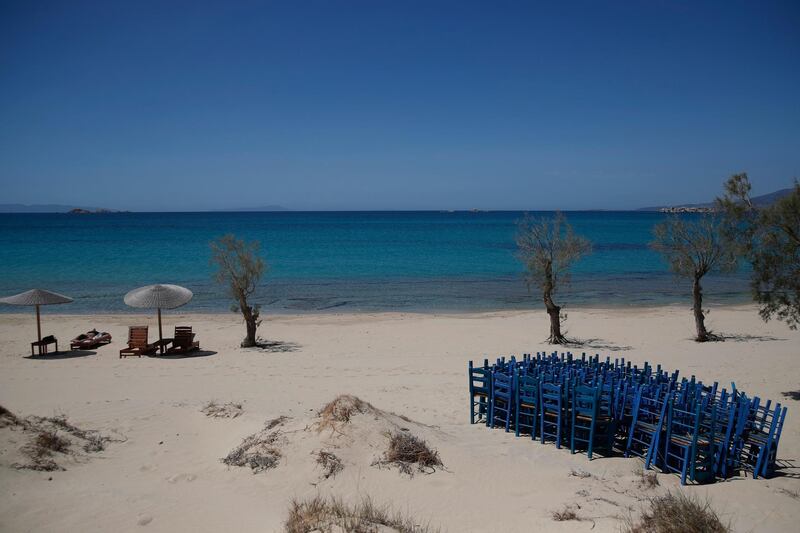 A tourist enjoys the sun as tavern chairs are stored at Plaka beach on the Aegean island of Naxos, Greece. (AP Photo/Thanassis Stavrakis)