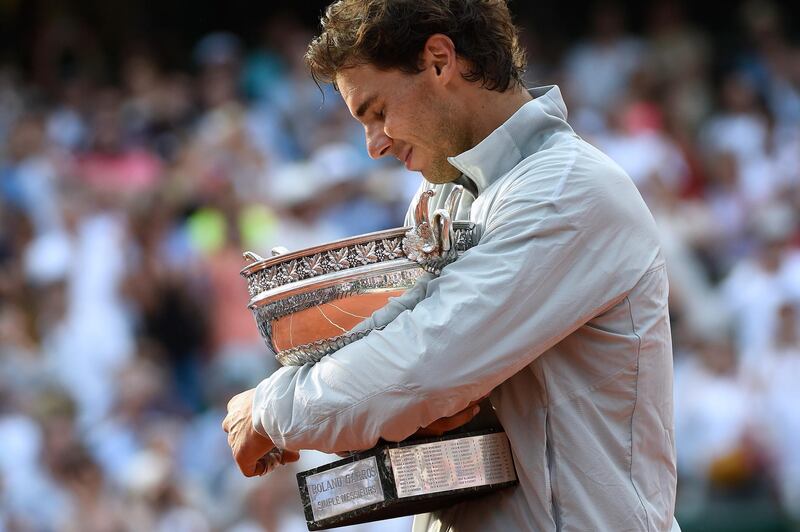Spain's Rafael Nadal reacts as he holds the Musketeers trophy after winning the French tennis Open men's final match against Serbia's Novak Djokovic at the Roland Garros stadium in Paris on June 8, 2014. AFP PHOTO / MIGUEL MEDINA (Photo by MIGUEL MEDINA / AFP)