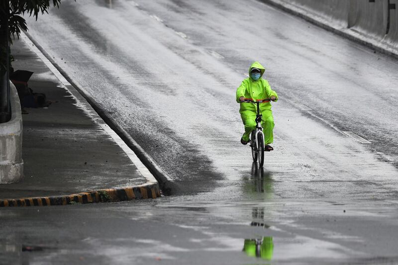 A man wearing a protective mask and raincoat rides his bicycle during rain caused by Typhoon Vongfong in Manila, Philippines.  AP