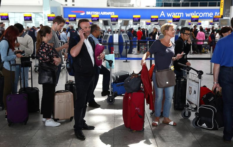 Passengers wait with their luggage at the British Airways check-in desks at Heathrow airport in London. Neil Hall / Reuetrs