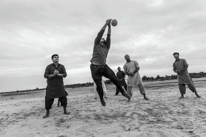 ABU DHABI, UNITED ARAB EMIRATES. 10 JANUARY 2020. Farm workers and laborers from Pakistan and India play an informal game of volleyball on a desolate patch of sand next to the Sheikh Mohammed Bin Rashid highway halfway between the Dubai and Abu Dhabi highway. (Photo: Antonie Robertson/The National) Journalist: STANDALONE. Section: Weekend.

