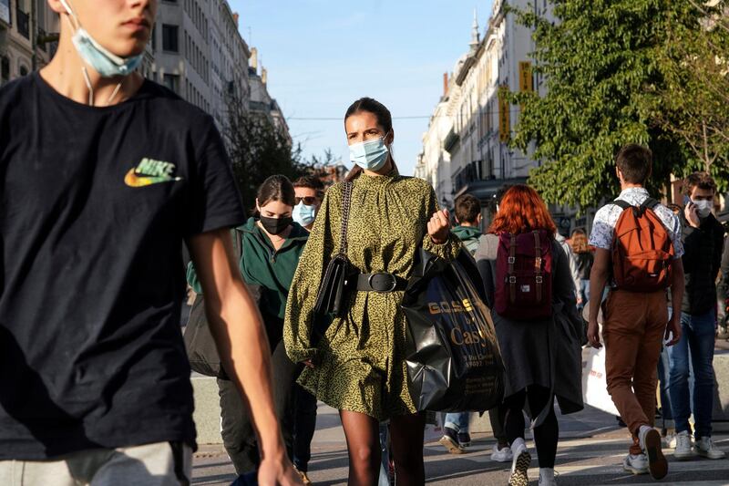 People wearing face masks cross the street in the center of Lyon, central France, Thursday, Oct. 8, 2020. French authorities have placed Lyon on maximum virus alert, banning festive gatherings and requiring all bars to close. (AP Photo/Laurent Cipriani)