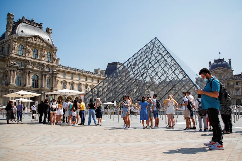 People wait to enter the Louvre museum in Paris. Museums, cinemas, theatres, tourist sites and other establishments attracting more than 50 visitors at any one time must demand proof of double vaccination or a recent negative Covid test as a condition of entry. Reuters