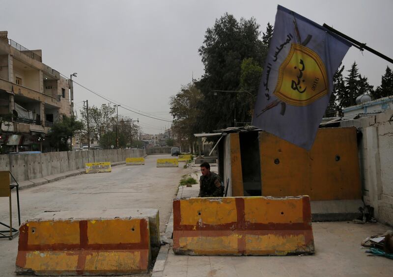 In this photo taken on Wednesday, March 28, 2018, a Syrian fighter from the Kurdish police, guards the entrance of the Manbij Military Council the Kurdish led militia group that defending Manbij, north Syria. Manbij, a mixed Arab and Kurdish town of nearly 400,000, was liberated from Islamic State militants in 2016 by the YPG fighters with backing from U.S-led coalition airstrikes. With Turkey's threats, the town has become the axle for U.S. policy in Syria, threatening its prestige and military deployment in eastern Syria. (AP Photo/Hussein Malla)