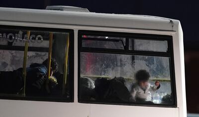 A group of people thought to be migrants wait to be transported onboard a bus after being brought into Dover, Kent. PA