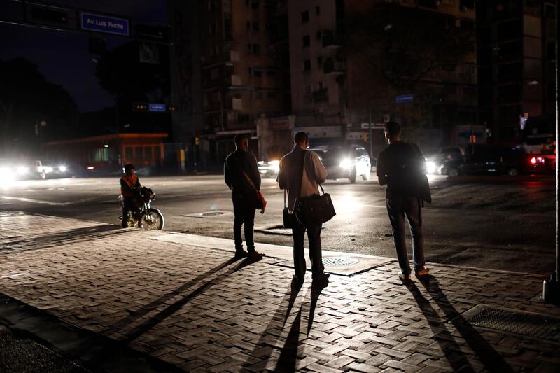 People wait for a public transportation on a street during a blackout in Caracas, Venezuela, Monday, July 22, 2019. The lights went out across much of Venezuela Monday, reviving fears of the blackouts that plunged the country into chaos a few months ago as the government once again accused opponents of sabotaging the nation's hydroelectric power system. (AP Photo/Ariana Cubillos)