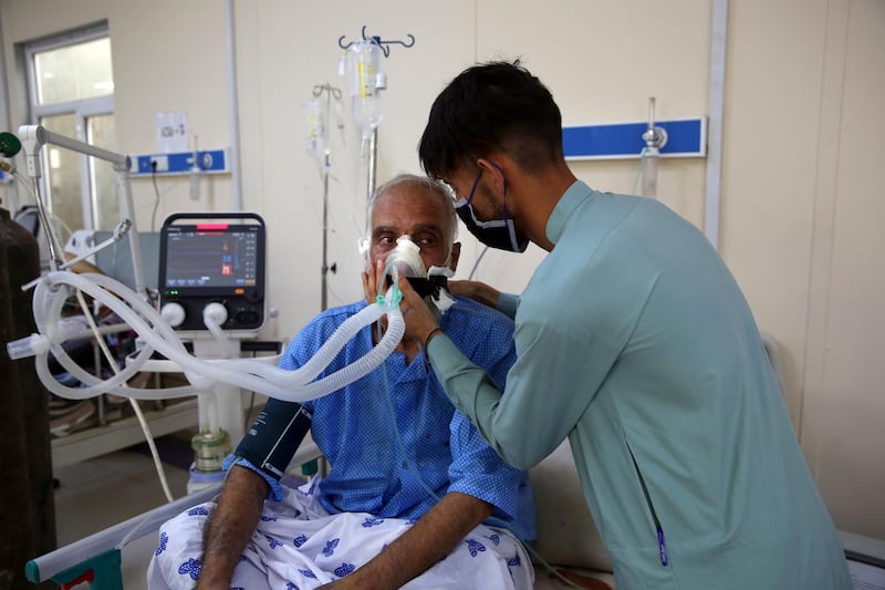Mohammad Amin is helped by his son in the ICU ward for COVID-19 patients at the Afghan-Japan Communicable Disease Hospital.
