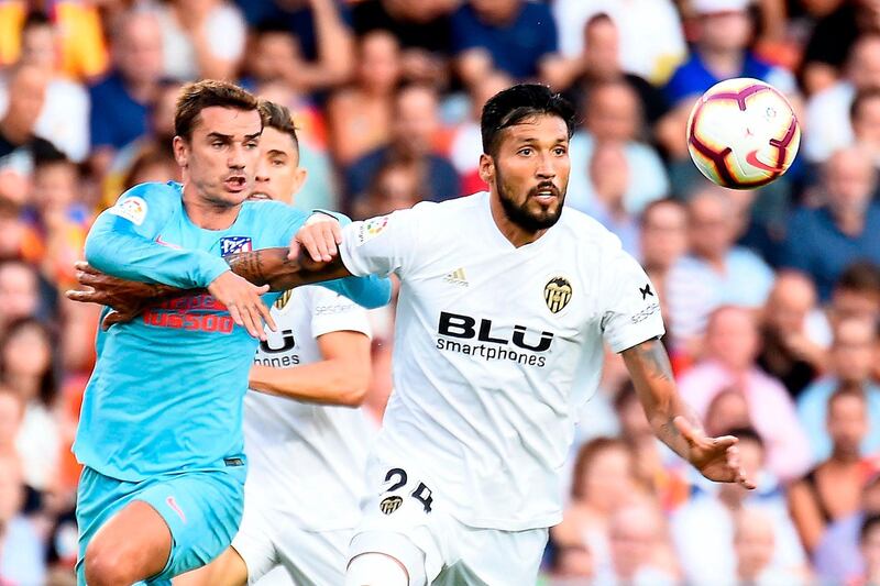 Atletico Madrid's French forward Antoine Griezmann challenges Valencia's Argentinian defender Ezequiel Garay (R) during the Spanish League football match between Valencia and Atletico Madrid at the Mestalla Stadium in Valencia on August 20, 2018. (Photo by JOSE JORDAN / AFP)