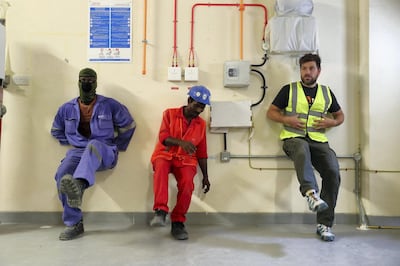 DUBAI ,  UNITED ARAB EMIRATES , JULY 3 – 2019 :- Hannes Loubser , fitness instructor with Iconic ( right ) giving tips for how to use wall for exercise to the DEWA construction workers during the fitness training session at the DEWA Sub Station near the International City in Dubai. ( Pawan Singh / The National ) For Lifestyle . Story by Melanie Swan