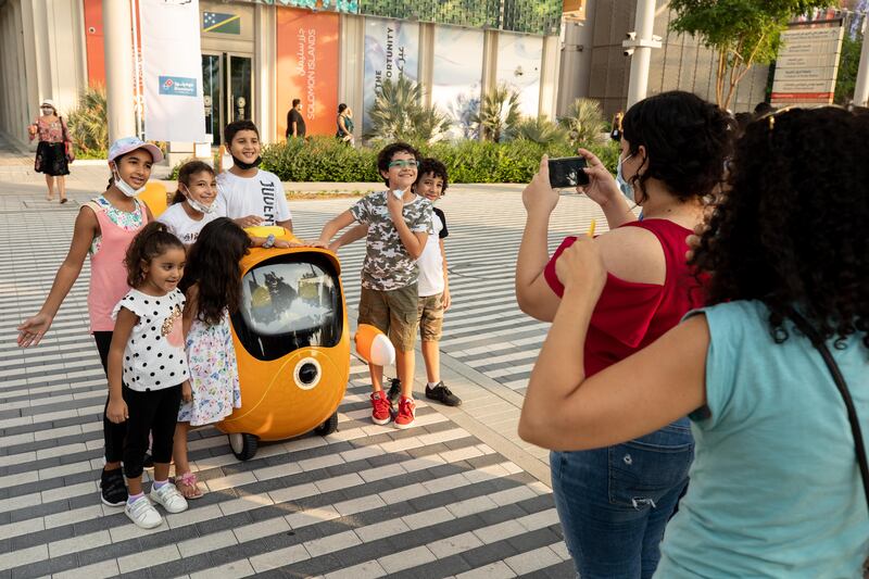 Children pose with Opti, one of the robot mascots at Expo 2020 Dubai. Photo: Christophe Viseux/Expo 2020 Dubai