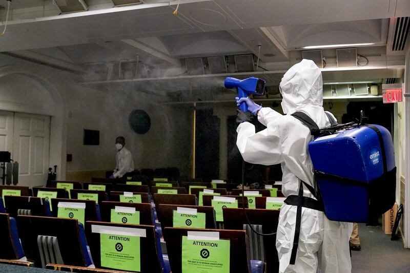 A member of the White House cleaning staff sprays disinfectant in the press briefing room before US President Donald Trump's return from Walter Reed Medical Centre. Reuters
