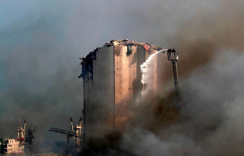 Lebanese firefighters stand on a ladder amid billowing smoke as they extinguish the remaining flames at the seaport of Beirut, a day after a huge fire erupted in warehouses. AFP