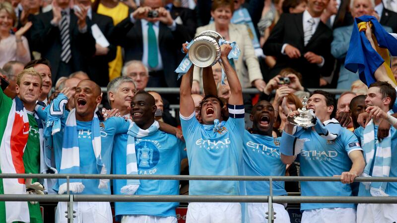 Manchester City's Carlos Tevez (C) lifts the trophy after defeating Stoke City in their FA Cup final soccer match at Wembley Stadium, in London May 14, 2011.   REUTERS/Eddie Keogh (BRITAIN  - Tags: SPORT SOCCER)   *** Local Caption ***  WEM526_SOCCER-ENGLA_0514_11.JPG