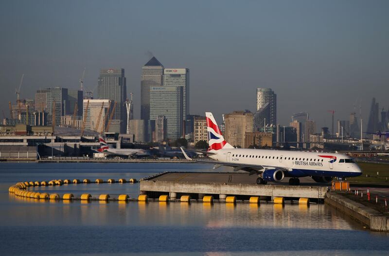 (FILES) In this file photo taken on October 27, 2017 A British Airways airplane waits on the runway with the towers and buildings of the Canary Wharf financial district in background before taking off at London City Airport in London. IAG, owner of several major airlines including British Airways and Spanish carrier Iberia, said on October 26, 2018 that its net profit climbed 12 percent in the third quarter despite higher fuel costs. Profit after tax grew to 1.1 billion euros ($1.25 billion) in the three months to September, compared with the third quarter a year earlier. / AFP / Daniel LEAL-OLIVAS
