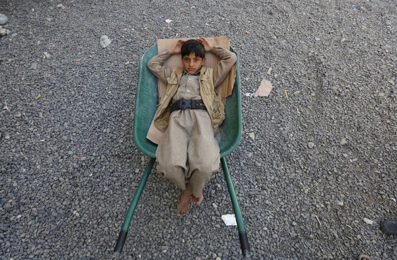 A boy lies in a wheelbarrow as he waits to receive food rations provided by Mona Relief Yemen in Sana'a, Yemen. EPA