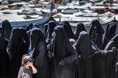 Women and a child queue to receive humanitarian aid packages at Al Hol in 2021. AFP