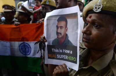 TOPSHOT - Indian security forces pose with the national flag and pictures of Indian Air Force pilot Abhinandan Varthaman during an event to pray for his return, at Kalikambal temple in Chennai on March 1, 2019. Thousands of Indians, some waving flags and singing, gathered March 1 to give a hero's welcome to an air force pilot due to be returned across the border after being shot down by Pakistan. / AFP / ARUN SANKAR
