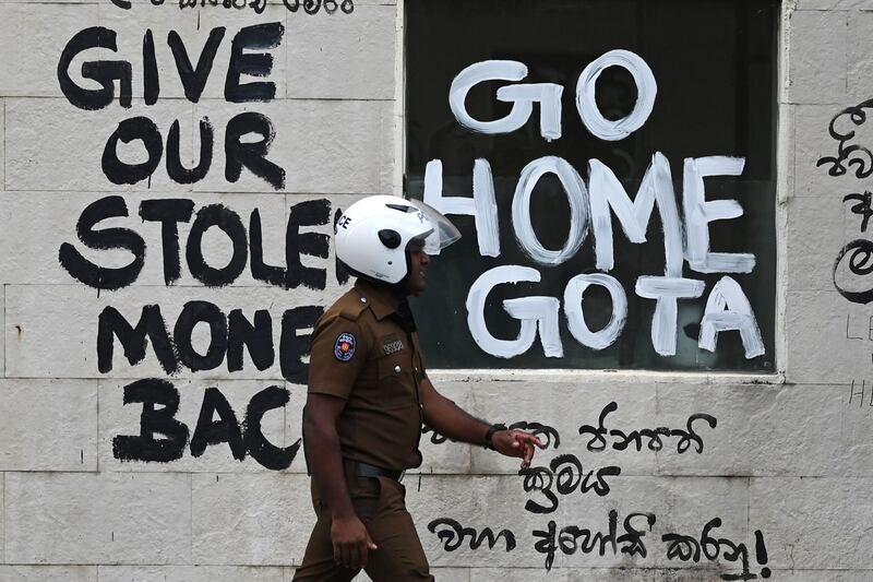 A policeman walks past slogans against the newly elected Sri Lankan President Ranil Wickramasinghe in Colombo. AFP