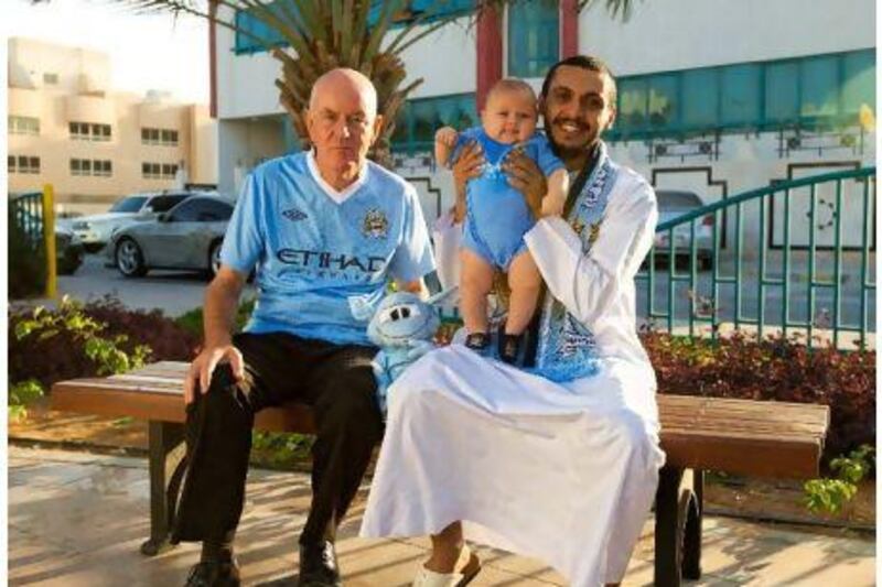 Three generations of Manchester City Fans. Father Mohammed Al Mansouri (right), with four-month old son Eid Mohammed Al Mansouri, and the boy’s grandfather, Peter Sneyd (left).