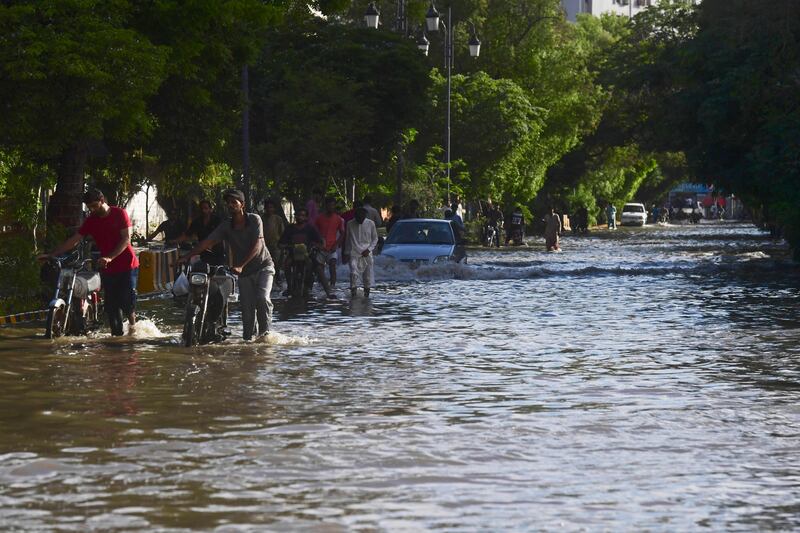 Motorists make their way through a flooded street after heavy rain. AFP