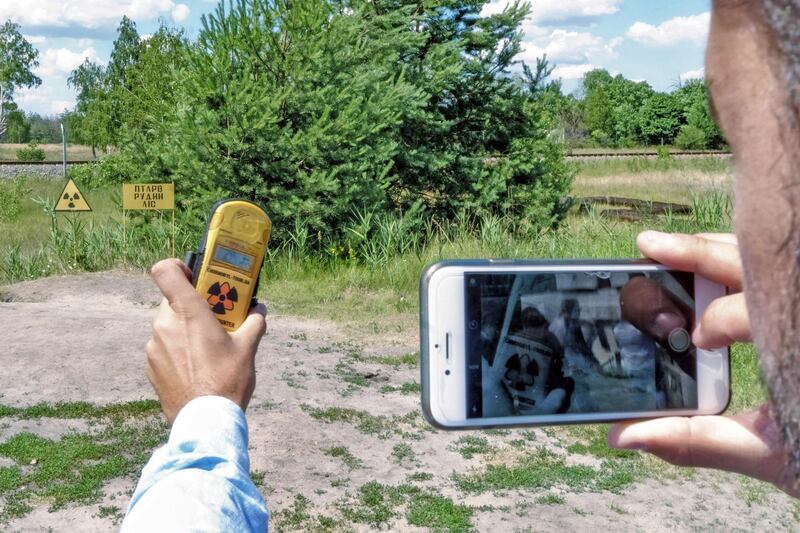 A tourist photographs the radiation reading on his dosimeter near a field with a high radiation level near Pripyat. Bloomberg