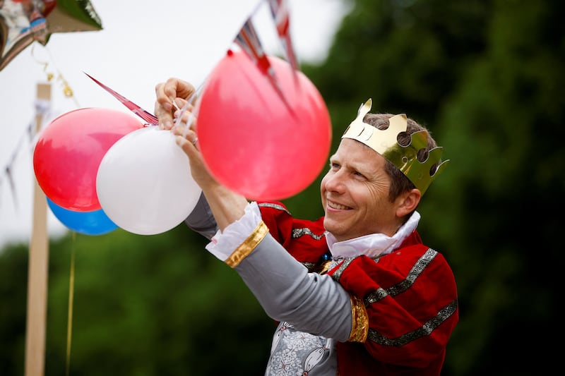 A man dressed as a king hangs decorations as he takes part in the Big Jubilee Lunch in Windsor. Reuters