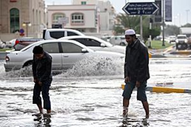 Pedestrians walk across a flooded intersection of Airport Road in Abu Dhabi during a rain storm on December 13.