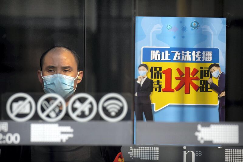 A security guard stands at the entrance of a shopping mall near a sign reminding people to keep at least one meter distance from each other in Beijing, Friday, Feb. 28, 2020. Japan's schools prepared to close for almost a month and entertainers, topped by K-pop superstars BTS, canceled events as a virus epidemic extended its spread through Asia into Europe and on Friday, into sub-Saharan Africa. (AP Photo/Mark Schiefelbein)