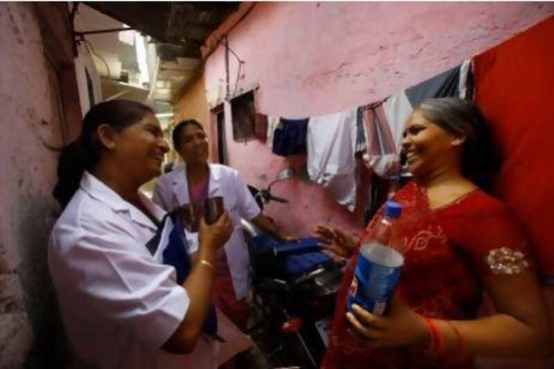 Usha Devi, right, who was suffering from cervical cancer, talks with health workers from Tata Memorial Hospital in a slum in Mumbai. Rafiq Maqbool / AP Photo