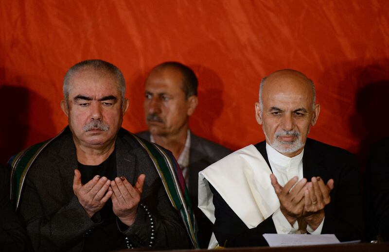 Abdul Rashid Dostum and Afghan President Ashraf Ghani pray during a press conference in Kabul in 2014. AFP